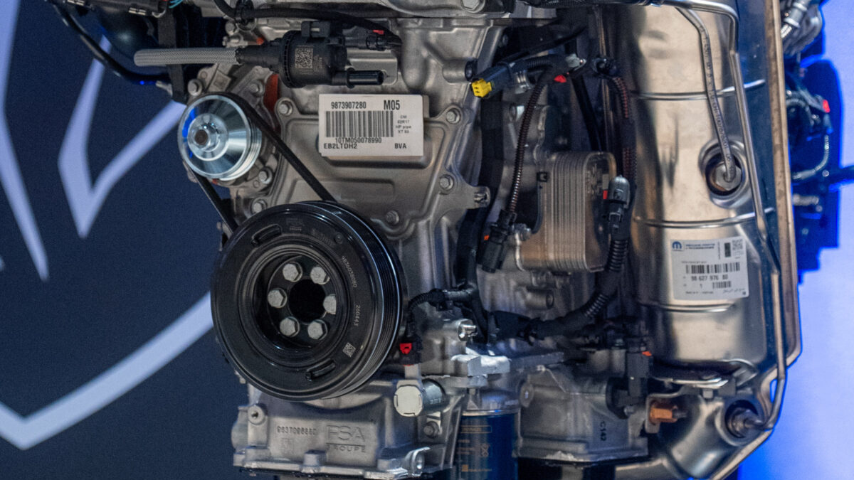El motor Peugeot Turbo 100 de frente, junto al cartel con su nombre