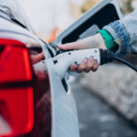 Woman charging her electric car with charging pistol