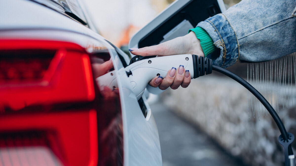 Woman charging her electric car with charging pistol
